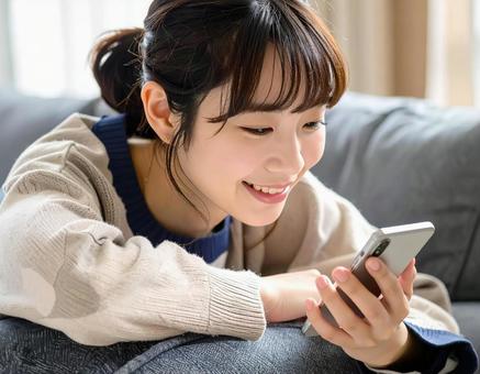 ソファでスマホを見る女性1 ソファでスマホを見る女性1の写真