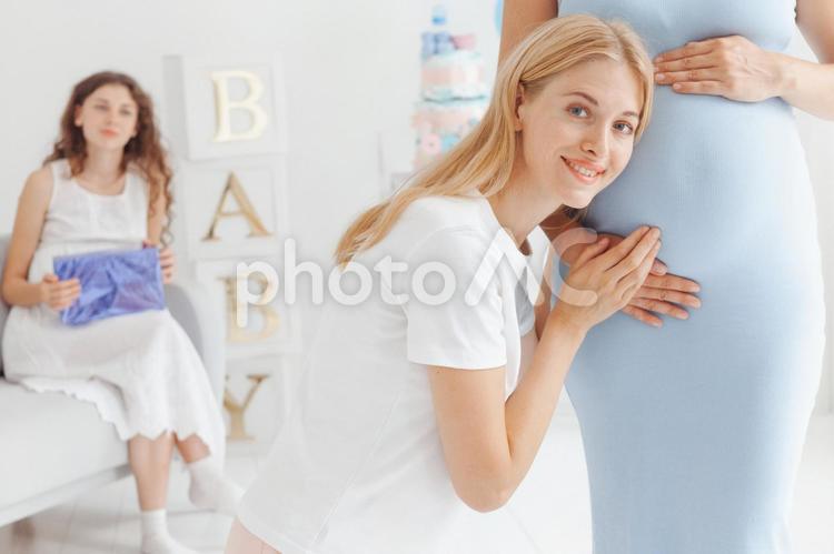 カメラ目線で妊婦の鼓動を聞いている女性 女性,人物,座るの写真素材