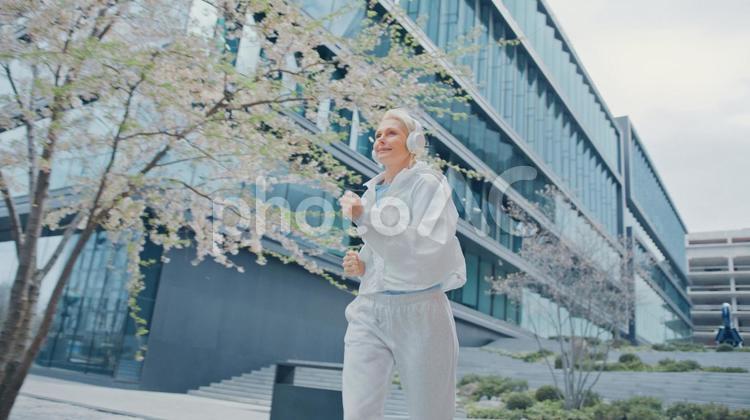 ビルの横をジョギングする女性 女性,人物,元気の写真素材