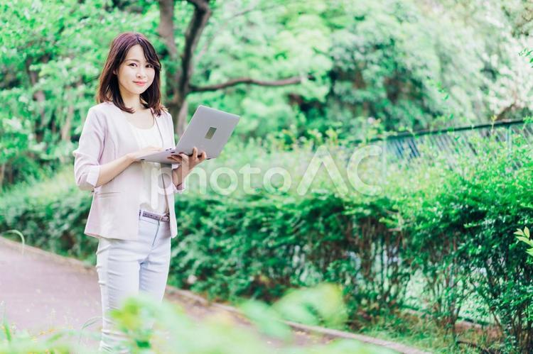外でパソコンを使う若いビジネスウーマン 外,白背景,外出の写真素材