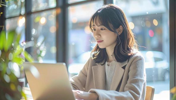 カフェでノートパソコンを使う日本人女性 カフェでノートパソコンを使う日本人女性の写真
