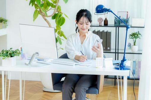 オフィスでスマホを持つビジネスウーマン スマホ,笑顔,ビジネスウーマンの写真素材