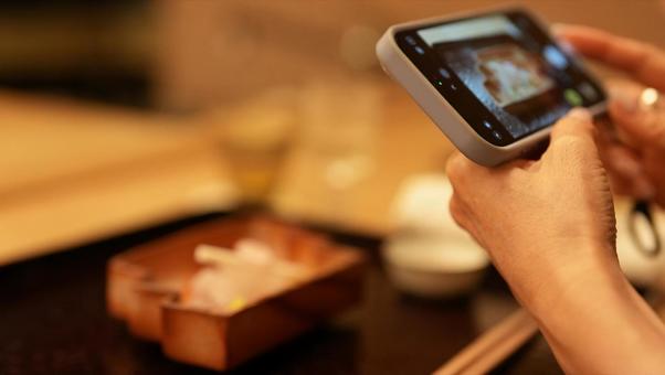 スマホで食べ物を撮影する女性 スマホで食べ物を撮影する女性の写真