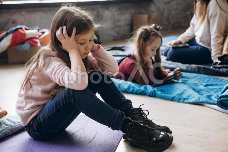 寝転んで頬杖をついてタブレットを見たり塞ぎ込む女の子 女の子,人物,貧困の写真素材