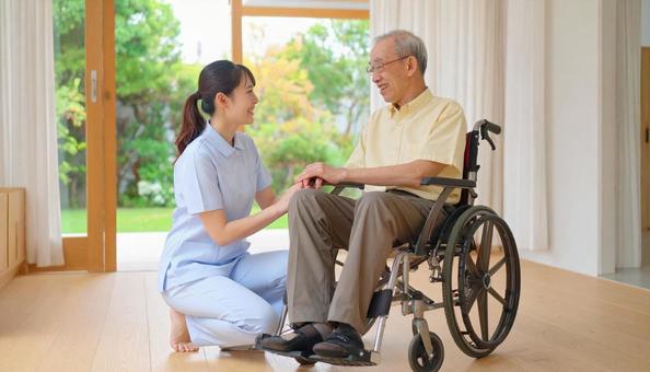 車椅子に乗った高齢男性と女性介護士 車椅子に乗った高齢男性と女性介護士の写真