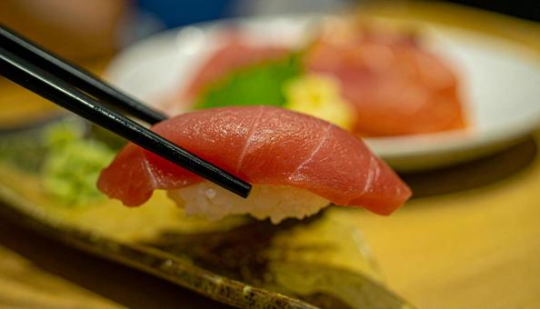 マグロ寿司を箸でつまむ マグロ寿司を箸でつまむの写真
