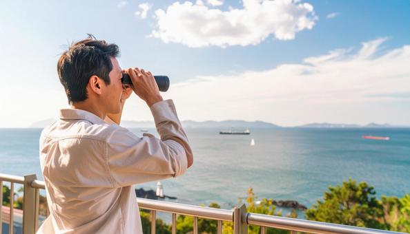 双眼鏡で海の先を見ている日本人男性 双眼鏡で海の先を見ている日本人男性の写真