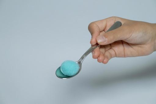 青い綿球を乗せたスプーンを持つ手 青い綿球,スプーン,手の写真素材