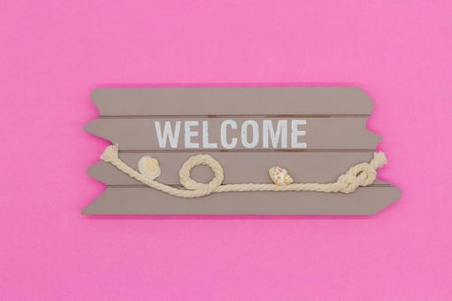 ピンク背景の「WELCOME」木の看板 ウェルカム,歓迎,ようこその写真素材