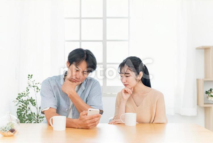 スマホを見る夫婦（困る）の写真