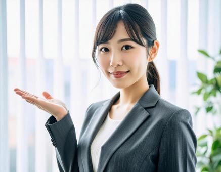 案内ポーズをするスーツ姿の女性 案内ポーズをするスーツ姿の女性の写真