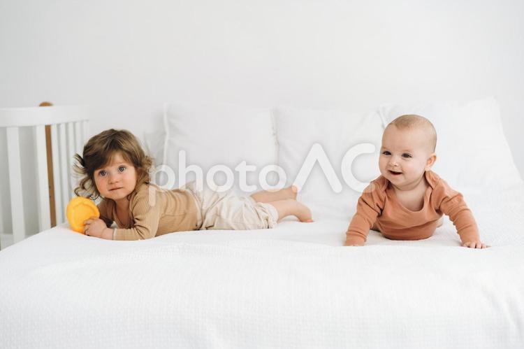 ベッドでうつ伏せになる赤ちゃんと男の子 赤ちゃん,かわいい,ベッドの写真素材