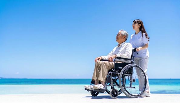 青空の下 同方向を見るシニア男性と介護士 青空の下 同方向を見るシニア男性と介護士の写真