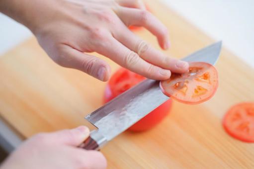 トマトを薄く輪切りにする手 トマトを薄く輪切りにする手の写真