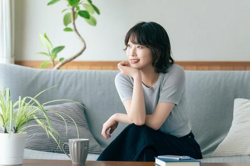 リビングのソファに座る笑顔の女性 女性,ソファ,微笑むの写真素材