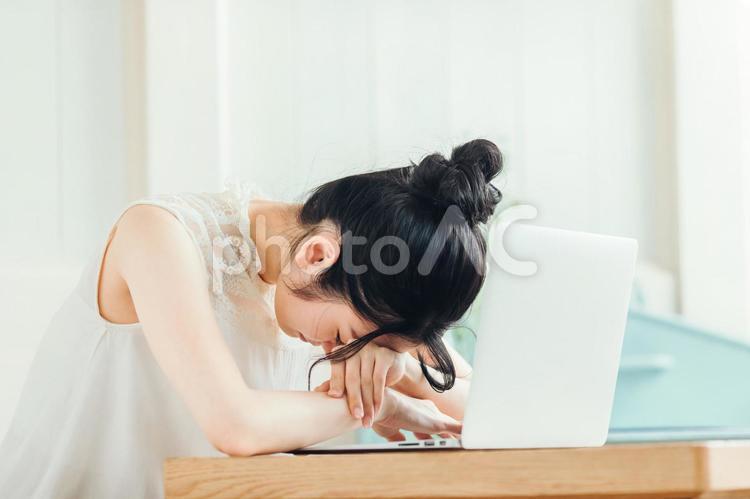 ノートパソコンの前でうずくまる受ける女性 悲しい,体調不良,ショックの写真素材
