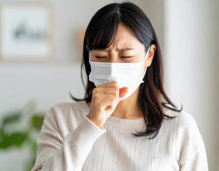 マスクを着用して咳をするの女性 マスクを着用して咳をするの女性の写真