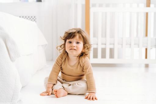 カメラ目線で座るベージュの服の子 カメラ目線で座るベージュの服の子 赤ちゃん,かわいい,お座りの写真素材