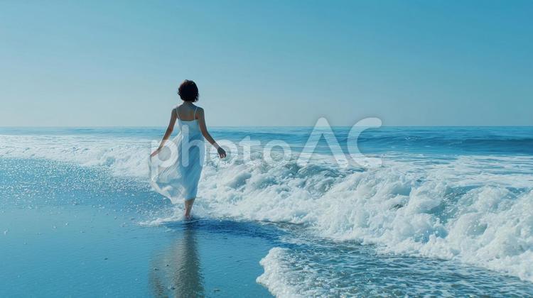 波打ち際を歩く白ワンピースの日本人女性 夏,海,波の写真素材