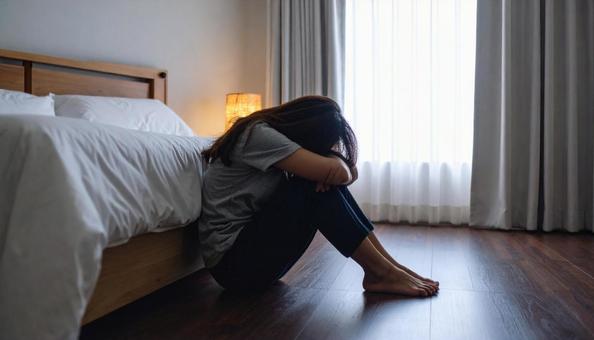 部屋で一人落ち込む女性 部屋で一人落ち込む女性の写真