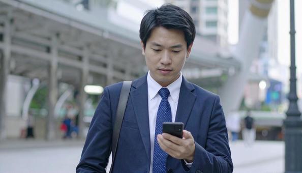 スマホを操作するビジネスマン スマホを操作するビジネスマンの写真