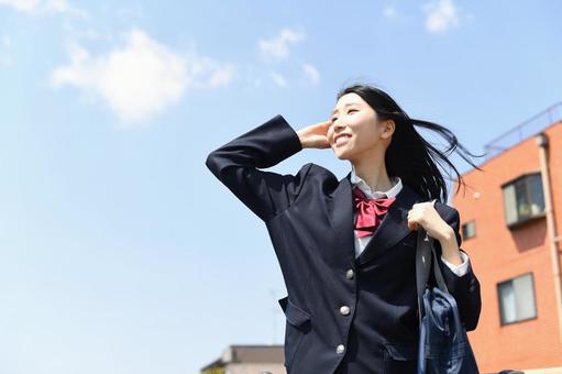 日本の女子高生が青空の下で笑顔で通学する 日本の女子高生が青空の下で笑顔で通学する 高校生,女子学生,学生の写真素材