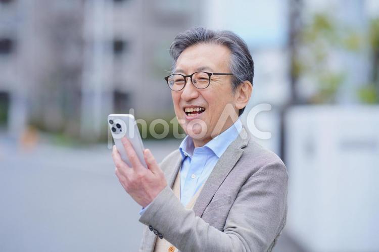 屋外でスマートフォンを使う笑顔の高齢男性 男性,おじいちゃん,1人の写真素材