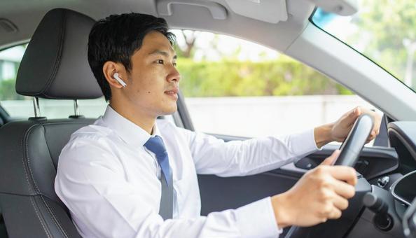 ワイヤレスイヤホンをつけて運転する男性 ワイヤレスイヤホンをつけて運転する男性の写真