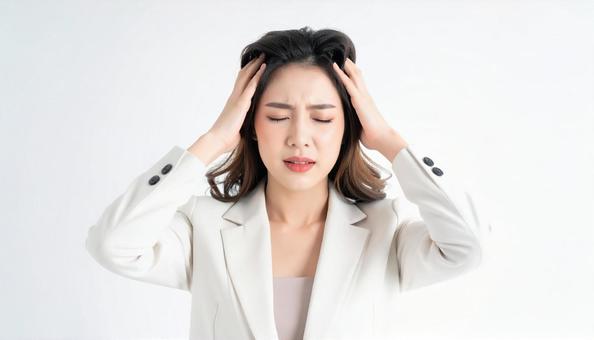 頭を押さえて悩むビジネスウーマンの表情の写真