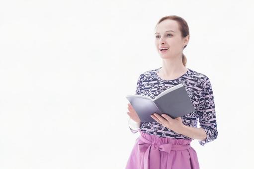 スケジュール帳を確認する若い女性 スケジュール帳を確認する若い女性 海外,スケジュール帳,外国人の写真素材