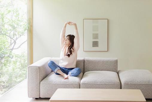 ソファでストレッチをする女性 ソファでストレッチをする女性 女性,人物,ストレッチの写真素材