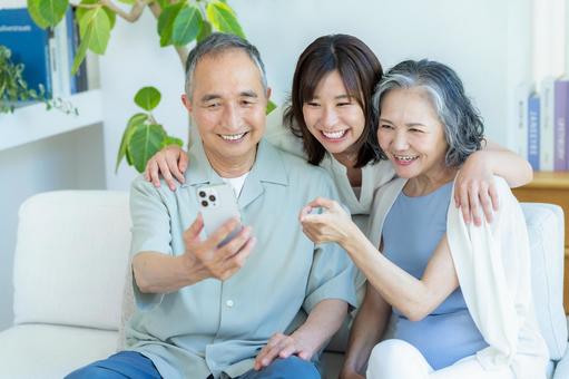 リビングでスマホを見るシニア夫婦と子供 シニア,夫婦,スマホの写真素材