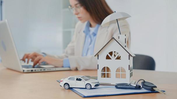 家と車の模型を置いて仕事をする女性 保険業,事務職,接客業の写真素材