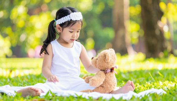 公園でテディベアと遊ぶ少女 公園でテディベアと遊ぶ少女の写真