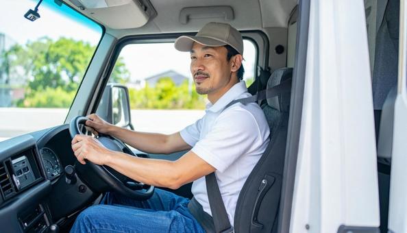 トラックを運転する男性ドライバーの横顔 トラックを運転する男性ドライバーの横顔の写真