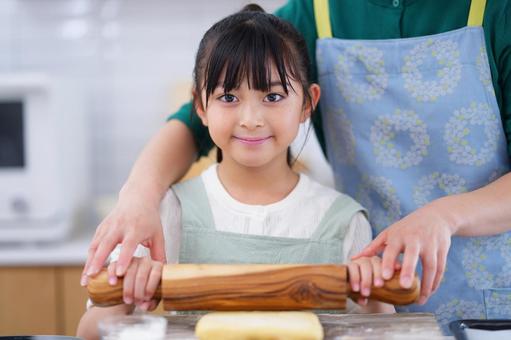 めん棒を持って笑顔を見せるエプロン姿の女の子 女の子,日本人,めん棒の写真素材