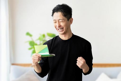 通帳を見て喜ぶ男性 通帳を見て喜ぶ男性 男性,給料,昇給の写真素材