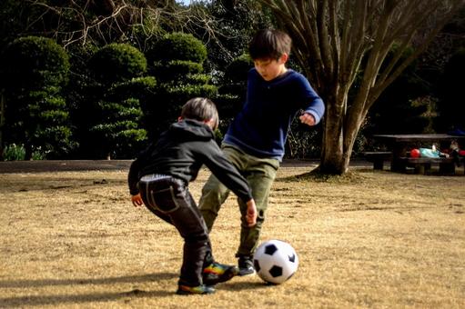 <素材>芝生の公園でサッカーをする兄弟 <素材>芝生の公園でサッカーをする兄弟 子供,サッカー,運動の写真素材