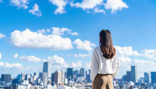 青空の下、遠くの景色を眺める女性の後ろ姿 青空の下、遠くの景色を眺める女性の後ろ姿の写真