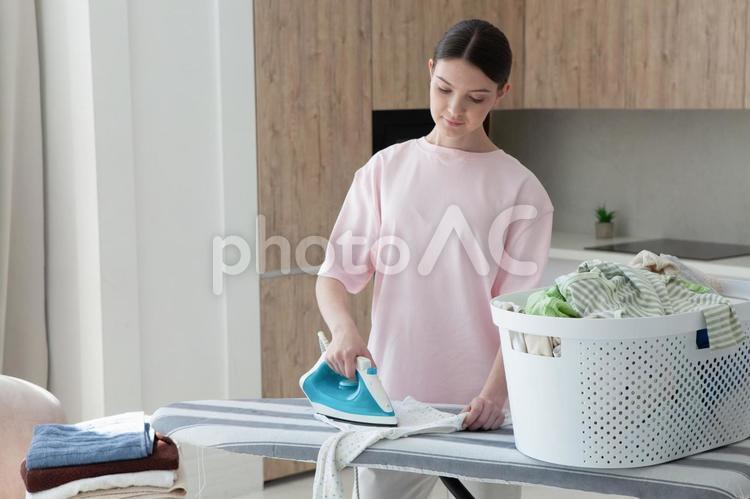 無表情でアイロンする女性 女性,人物,立つの写真素材