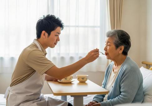 男性介護士が高齢女性に食事介助する場面の写真