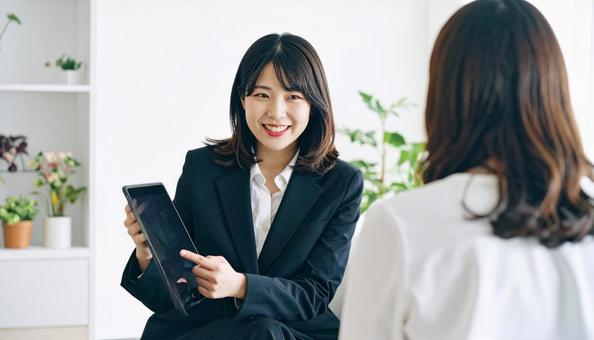 タブレットを使って説明する女性営業マン タブレットを使って説明する女性営業マンの写真