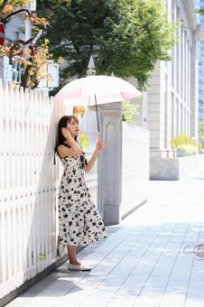 白い塀にもたれて景色を眺める女性 白い塀にもたれて景色を眺める女性の写真