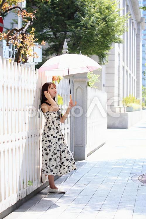 白い塀にもたれて景色を眺める女性 女性,美人,日傘の写真素材