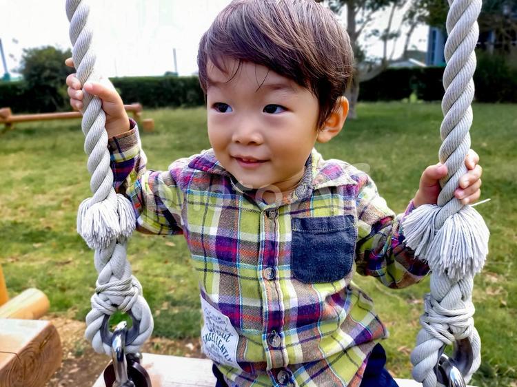 ＜素材＞春の公園でブランコで遊ぶ男の子 子供,笑顔,ブランコの写真素材