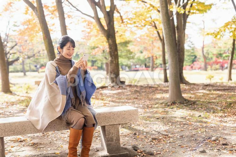 秋の公園でスマホを持った女性 スマホ,スマートフォン,5gの写真素材