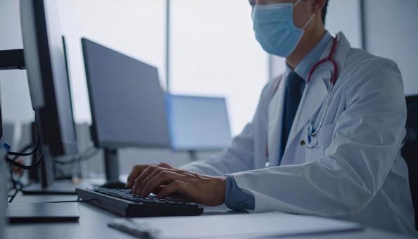 病院で電子カルテに入力する男性の手もとの写真