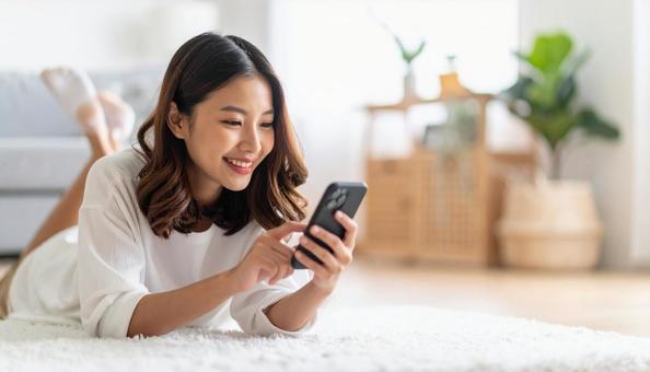 リビングで横になりスマホを操作する女性の写真