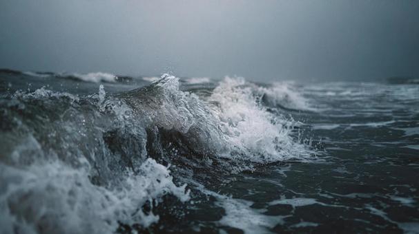 暗い海に立つ荒々しい波と水しぶきの写真