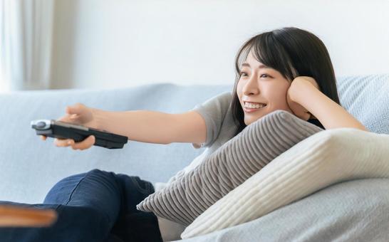 ソファに寝転んでテレビを見る女性 ソファに寝転んでテレビを見る女性 女性,テレビ,ソファの写真素材